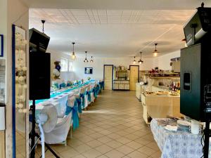 un restaurant avec des tables blanches et des nappes bleues et blanches dans l'établissement Goldschmiedt Vendégház, à Pálköve