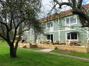 una casa verde con una terraza de madera y un árbol en The Green House Guesthouse, en Sunnemo