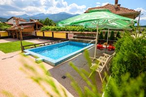 een zwembad met een parasol en een tafel en stoelen bij Guest House Dinaya in Dobrinishte