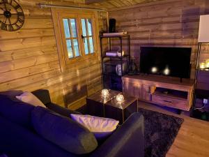 ein Wohnzimmer mit einem Sofa und einem Flachbild-TV in der Unterkunft Bien-être au rendez-vous - Spa Privatif in Blaton