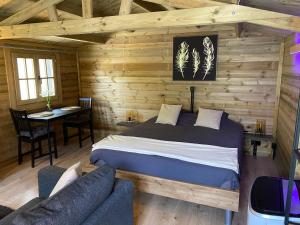 1 dormitorio con 1 cama en una cabaña de madera en Bien-être au rendez-vous - Spa Privatif, en Blaton
