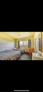 Tekao Lodge في Te Kao: غرفة فندقية بسريرين وطاولة