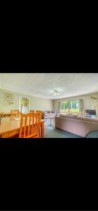 Tekao Lodge في Te Kao: غرفة معيشة مع طاولة وكراسي وأريكة