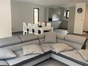 ラカノーにあるMAISON moderne avec piscine chaufféeのリビングルーム(グレーのソファ付)、キッチンが備わります。