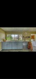 a kitchen with white cabinets and a large window at Tekao Lodge in Te Kao