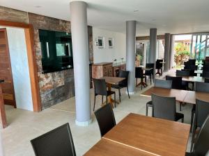 a dining room with tables and chairs and a wall of windows at Pousada Pénareia in Morro de São Paulo