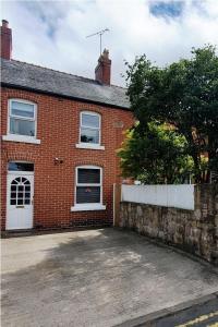 ein rotes Backsteinhaus mit einer weißen Tür und Fenstern in der Unterkunft Entire town house with free parking in Oswestry