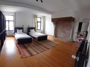 ein Wohnzimmer mit 2 Betten und einem Kamin in der Unterkunft Haras & Hotel Petit-Hallet in Hannut