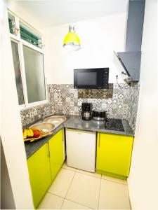 a small kitchen with yellow cabinets and a sink at T2 Jacuzzis et piscine au centre ville de Port-Louis in Port-Louis