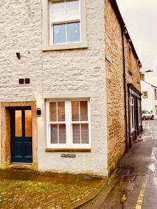 a white building with a blue door on a street at Folly View - Settle in Settle