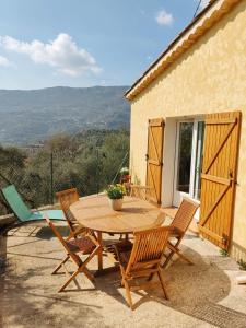 einen Holztisch und Stühle auf einer Terrasse in der Unterkunft Bas de villa. Côte d'Azur, à 20 kms de Nice in Contes