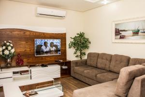uma sala de estar com um sofá e uma televisão de ecrã plano em Casa Petri Gramado em Gramado