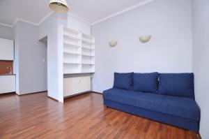 a blue couch in a living room with a wooden floor at Studio Sopot Sklodowskiej-Curie in Sopot