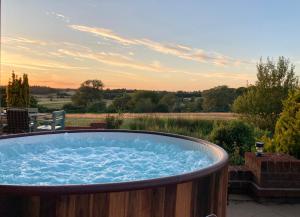 a jacuzzi tub with a view of a field at Kingfisher Nook at Waveney Farm in Hoxne