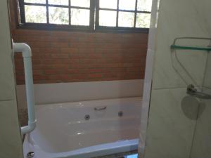 uma casa de banho com uma banheira e uma janela em CHALÉ NATIVO R Júlio Miranda nº 06 em Conceição do Ibitipoca