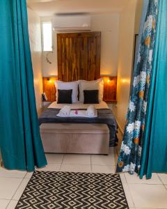 Schlafzimmer mit einem großen Bett und blauen Vorhängen in der Unterkunft Studio jacuzzis et piscine au centre ville de Port-Louis in Port-Louis