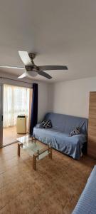 een woonkamer met een blauwe bank en een plafondventilator bij Apartamento Sun Beach Poniente Benidorm in Benidorm