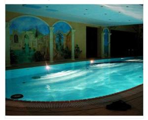 a large swimming pool with blue water in a building at Apartament Małgosi in Malbork