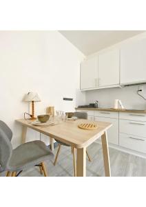 a white kitchen with a wooden table and chairs at Coup de Coeur au pied du château - Nice studio ideally located in Annecy