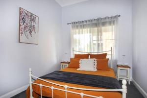 a bedroom with a bed with orange and white pillows at Black Possum Cottage Views of the Bay in Pindimar