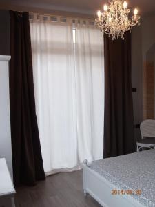 a bedroom with a white curtain and a chandelier at Casa Vacanze SanGiacomo in Santo Stefano al Mare