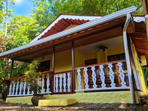 a small yellow house with a white railing at Jungle Beach Bungalow with AC & Fiber optic in Puerto Viejo +5 photos