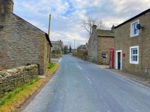 an empty road in a village with stone buildings at Olde Post House, Rathmell - Settle in Settle