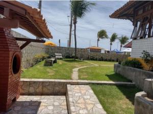 a backyard with a bench and palm trees and a wall at Aconchegante Apt FRENTE AO MAR in Barra de São Miguel