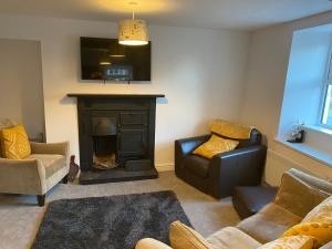 a living room with a fireplace and a couch and chairs at Olde Post House, Rathmell - Settle in Settle