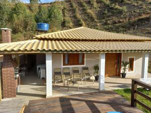 ein Haus mit einem Dach mit Stühlen und einem Tisch in der Unterkunft Recanto do Pimenta in Pedra Azul