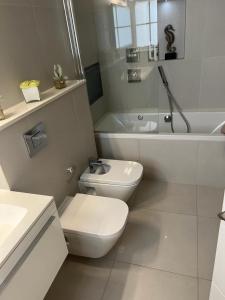 a white bathroom with a toilet and a bath tub at Hestia Travel Mayfair London in London