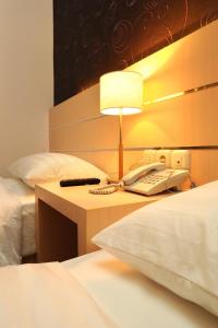 a hotel room with a phone and a bed at Cordela Hotel Medan in Medan