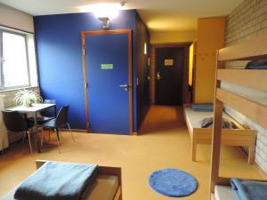 um quarto com uma porta azul e uma mesa e uma cama em Hostel Blauwput Leuven em Lovaina