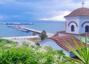 a building with a tile roof next to the ocean at Blue Moon Apartments in Nea Michaniona