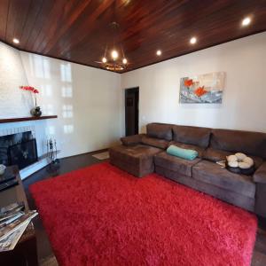 sala de estar con sofá marrón y alfombra roja en Casa Avelar Campos do Jordão, en Campos do Jordão