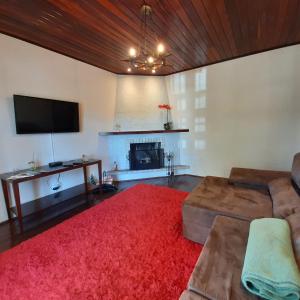 sala de estar con sofá y TV de pantalla plana en Casa Avelar Campos do Jordão, en Campos do Jordão