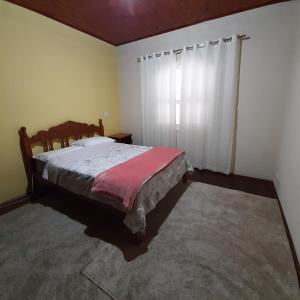 1 dormitorio con 1 cama con manta roja en Casa Avelar Campos do Jordão, en Campos do Jordão