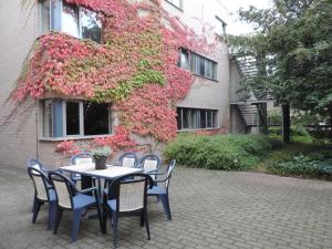 a table and chairs in front of a building with flowers at Hostel Blauwput Leuven in Leuven