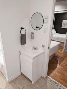 a bathroom with a sink and a mirror and a bed at Hébergement Harvey in Alma