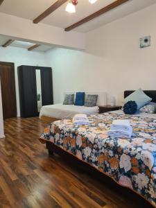 a bedroom with two beds and a wooden floor at Luca's House ( aeroport Henry Coanda, Therme Bucuresti) in Baloteşti