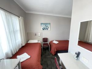 a hotel room with two beds and a television at Hillview Motel in Goulburn