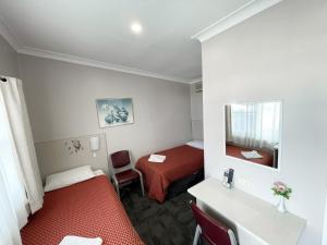 Habitación pequeña con 2 camas y espejo. en Hillview Motel en Goulburn
