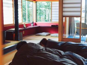 a person laying on a couch in a room with windows at WABISABI ISURUGI KASHIWAYA - Vacation STAY 34839v in Oyabe