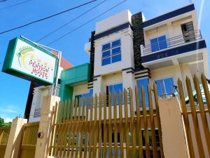 ein weißes Haus mit einem Zaun und einem Schild in der Unterkunft Golden Pension House,Palawan in Puerto Princesa