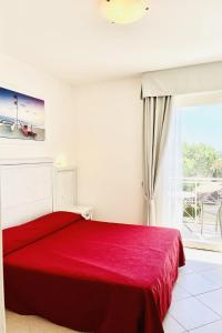 a red bed in a white room with a window at HOTEL PIGALLE in Forte dei Marmi