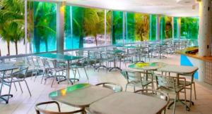 a cafeteria with tables and chairs and a green wall at AP Alecrim Porto Real Suítes com Tela de Proteção Praia Privativa in Mangaratiba