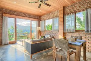 a living room with a couch and a table and windows at Romantic Barn with Mt. Agung Views in Sidemen
