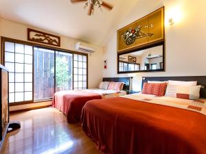 a bedroom with two beds and a couch and windows at Maguro House in Osaka
