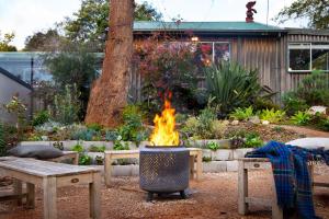 a fire pit in a yard with a table and benches at Cornish Hill House in Daylesford