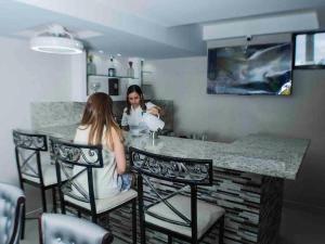 duas mulheres sentadas num bar numa cozinha em Malecon Cozy - Premium Plus 10 em Santo Domingo